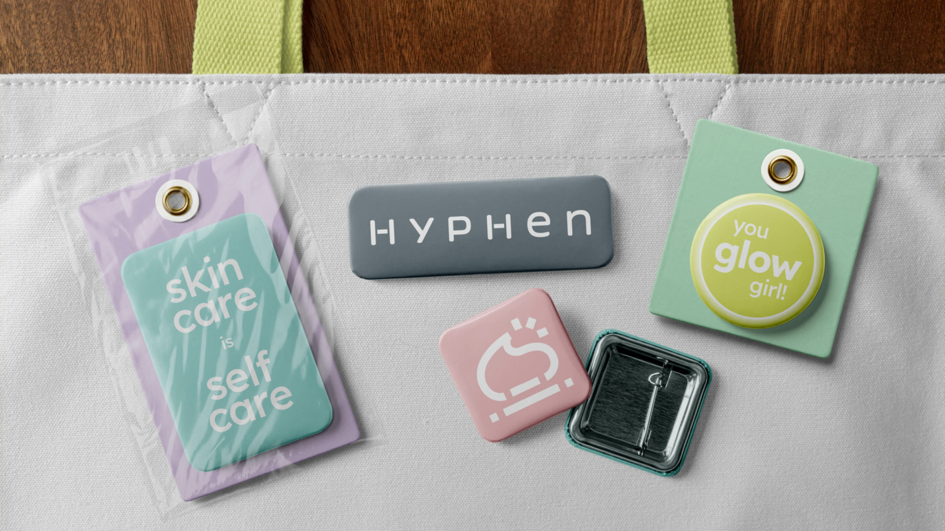 Hyphen merchandise including pins and a tote bag