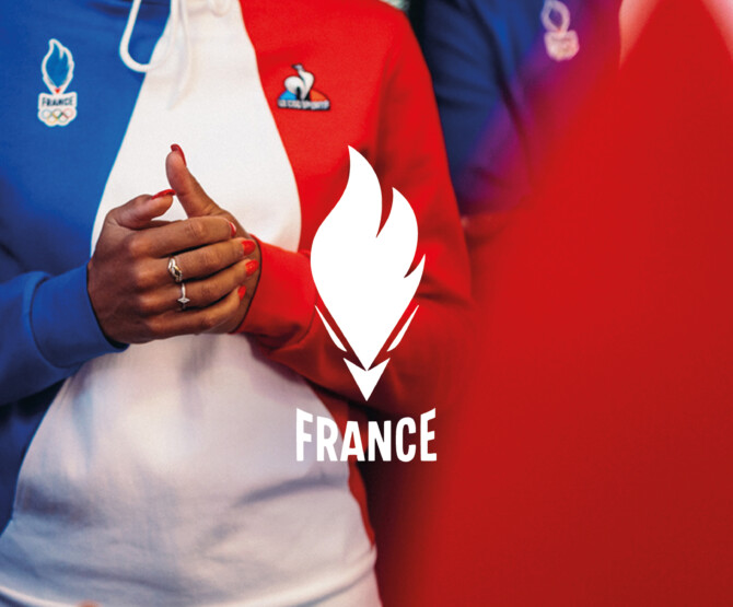 Woman in blue, white, red jumper standing behind French teams logo